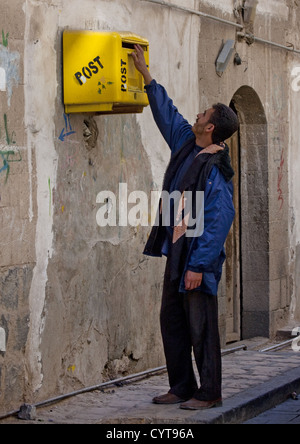 Mann Posten Briefe In A seltsam hoch platziert gelben Briefkasten, Sanaa, Jemen Stockfoto