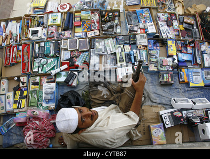 Verkäufer mit einer Pistole und sitzt unter der Artikel zum Verkauf, Tarim Markt, Jemen Stockfoto