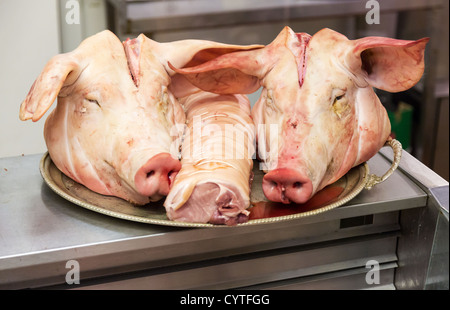 Paar Schweine Köpfe auf Tablett in einem Metzger-Shop mit einem starrte auf den Betrachter Stockfoto