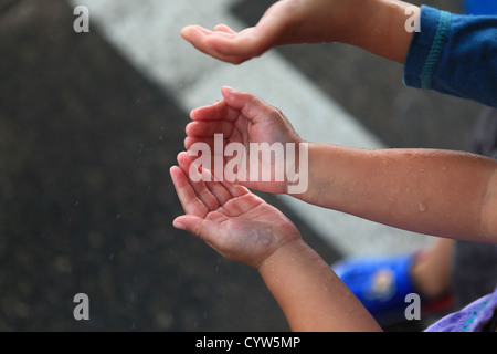 Regentropfen auf die Hände des Kindes Stockfoto