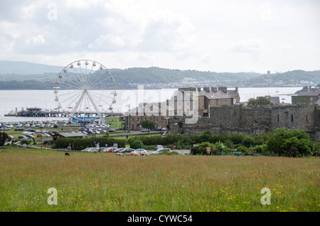 BEAUMARIS, Wales – Ein Riesenrad steht an prominenter Stelle unter den Dächern von Beaumaris auf der Isle of Anglesey. Die Küstenstadt liegt an der Menai-Straße, dem Gewässer, das Anglesey vom Festland von Wales trennt. Beaumaris liegt an der Südostküste der Insel und ist bekannt für seine Burg aus dem 13. Jahrhundert, die Eduard I. während seiner Eroberung von Wales erbaute. Die Stadt ist ein beliebtes Reiseziel auf Anglesey, der größten Insel in Wales. Die Menai-Straße, die über die Stadt hinaus sichtbar ist, ist ein schmaler Gezeitenwasserweg, der der Region historisch strategische Bedeutung verliehen hat. Stockfoto