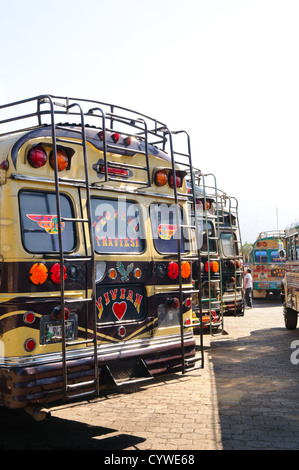Hühnerbusse Antigua Guatemala | ANTIGUA GUATEMALA, Guatemala — Bunt bemalte Hühnerbusse säumen eine Straße in Antigua Guatemala. Diese umgebauten amerikanischen Schulbusse, geschmückt mit lebhaften Designs und Chromzubehör, stehen bereit, um Einheimische und abenteuerlustige Touristen zu transportieren, und verkörpern Guatemalas lebendige Transportkultur vor dem Hintergrund kolonialer Architektur. Stockfoto
