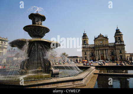 GUATEMALA CITY, Guatemala – Brunnen im Parque Central (offiziell Plaza de la Constitucion) im Zentrum von Guatemala City, Guatemala. Im Hintergrund links befindet sich die Catedral Metropolitana. Stockfoto