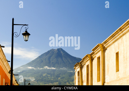 ANTIGUA GUATEMALA, Guatemala – im Vordergrund steht die traditionelle spanische Kolonialarchitektur Antiguas, im Hintergrund ragt der Volcán de Agua (oder der Vulkan Agua). Antigua Guatemala ist berühmt für seine gut erhaltene spanische Barockarchitektur sowie eine Reihe von Erdbebenruinen und gehört zum UNESCO-Weltkulturerbe und ehemalige Hauptstadt Guatemalas. Stockfoto