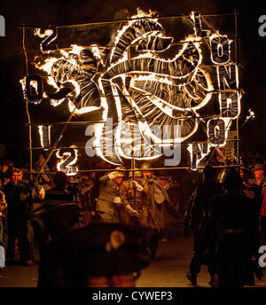 Lagerfeuer-Prozession zur Erinnerung. Tausende von Zuschauern Linie der Straßen von der winzigen East Sussex Dorf von East Hoathly in der Nähe von Lewes, UK Uhr Feuer Banner in Flammen als einen Akt der Erinnerung auf dem Weg in eine riesige Holzskulptur Lagerfeuer und Feuerwerk Anzeige durchgeführt. Stockfoto