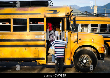 Hühnerbusse Antigua Guatemala | ANTIGUA GUATEMALA, Guatemala — Bunt bemalte Hühnerbusse säumen eine Straße in Antigua Guatemala. Diese umgebauten amerikanischen Schulbusse, geschmückt mit lebhaften Designs und Chromzubehör, stehen bereit, um Einheimische und abenteuerlustige Touristen zu transportieren, und verkörpern Guatemalas lebendige Transportkultur vor dem Hintergrund kolonialer Architektur. Stockfoto