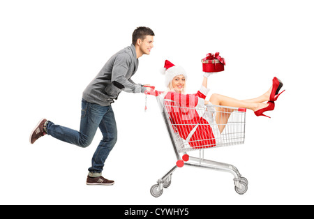 Glücklicher Kerl schob ein Weibchen tragen Weihnachtskostüm in einem Einkaufswagen isoliert auf weißem Hintergrund Stockfoto