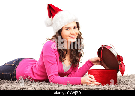 Lächelnde Frau mit Weihnachtsmütze hinlegen und öffnen ein Geschenk isoliert auf weißem Hintergrund Stockfoto