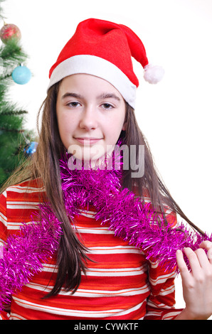 Porträt des jungen Mädchens tragen Mütze, in der Nähe von Weihnachtsbaum, Blickkontakt, vertikalen Schuss stehend Stockfoto