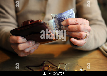 weibliche Rentner Geld in ihren arthritischen Händen hält Stockfoto