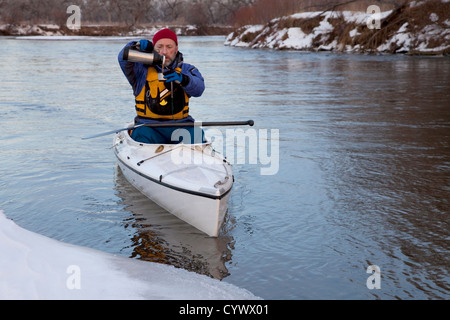 Winter-Kanu paddeln auf vereisten Fluss, eine Pause für heißen Tee (South Platte River in Ost-Colorado) Stockfoto