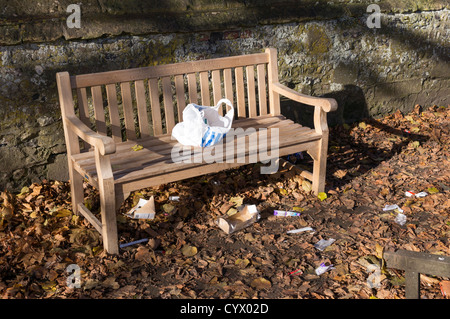 Tesco-Tragetasche und Müll hinterlassen hölzerne Parkbank Stockfoto