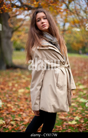 Porträt einer schönen Frau, die auf einem Feld mit Herbst goldene Blätter fallen, Green Park, London, England, UK. Stockfoto