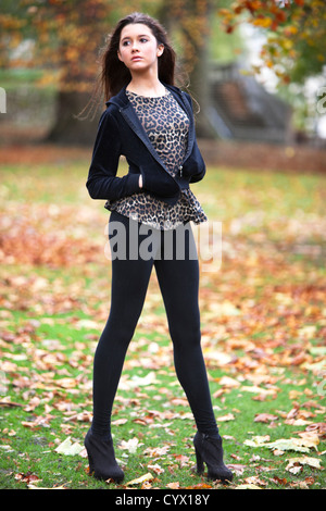 In voller Länge Porträt einer schönen Frau, die auf einem Feld mit Herbst goldene Blätter fallen, Green Park, London, England, UK. Stockfoto