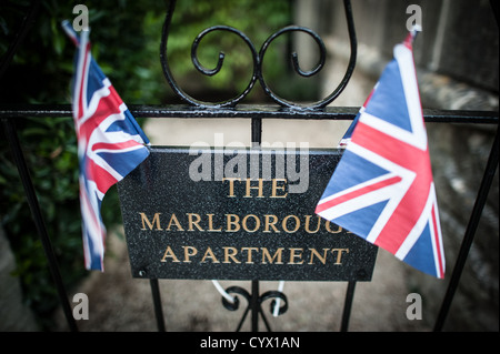 BATH, Vereinigtes Königreich — kleine Union Flag Wimpel umrahmen das Schild für das historische Apartment Marlborough in Royal Crescent, Bath, Somerset. Die Marlborough Apartments sind eine Touristenattraktion, die die Innenarchitektur der Apartments aus der edwardianischen Ära zu ihrer Blütezeit bewahrt. Der Royal Crescent, ein ikonisches Beispiel georgianischer Architektur, ist eines der berühmtesten Wahrzeichen von Bath. Stockfoto