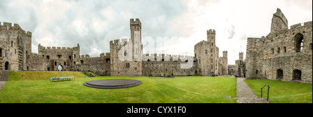 CAERNARFON, Wales – Ein Panorama des Inneren von Caernarfon Castle im Nordwesten von Wales. Die Schieferdais im Zentrum wurde für die Einführungszeremonie von Prinz Charles als Prinz von Wales verwendet. Ursprünglich stand an der Stelle eine Burg aus dem späten 11. Jahrhundert, aber im späten 13. Jahrhundert ließ König Eduard I. ein neues Gebäude in Auftrag geben, das bis heute besteht. Es hat markante Türme und ist eines der am besten erhaltenen Burgen der Reihe, die Edward I. in Auftrag gab. Stockfoto