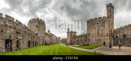 CAERNARFON, Wales – Ein Panorama des Innenhof von Caernarfon Castle im Nordwesten von Wales. Ursprünglich stand an der Stelle eine Burg aus dem späten 11. Jahrhundert, aber im späten 13. Jahrhundert ließ König Eduard I. ein neues Gebäude in Auftrag geben, das bis heute besteht. Es hat markante Türme und ist eines der am besten erhaltenen Burgen der Reihe, die Edward I. in Auftrag gab. Stockfoto