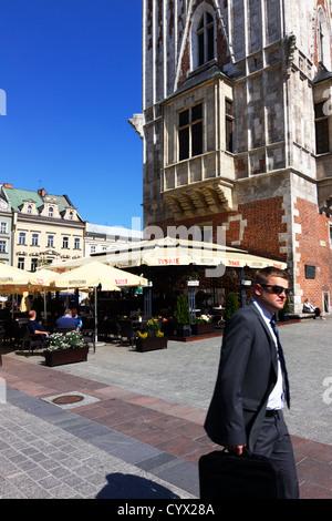 Junger Geschäftsmann im Anzug mit Aktentasche und Sonnenbrille am Hauptplatz in Krakau. Polen Stockfoto
