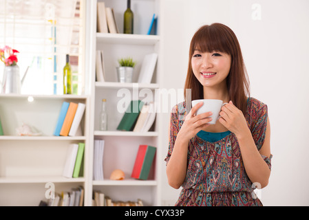 Aisan Mädchen genießen Kaffee in ihrem Wohnzimmer Stockfoto