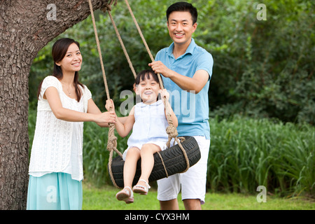 Fröhliche Familie spielen auf einer Schaukel im freien Stockfoto