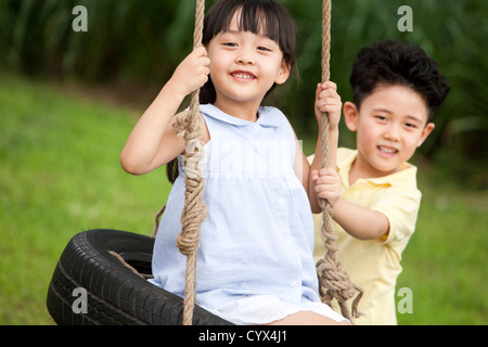 Glückliche Kinder spielen auf einer Schaukel Stockfoto