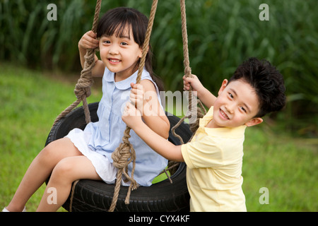 Fröhliche Kinder spielen auf einer Schaukel Stockfoto