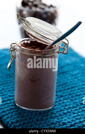 Nahaufnahme von Kakaopulver und Löffel im Glas mit Kaffeebohnen im Hintergrund Stockfoto