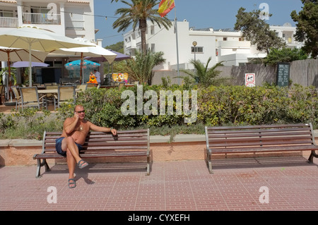 Ein Urlauber in Calla Llonga, Ibiza mit seinem Handy. Stockfoto