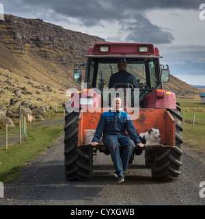 Teenager und seinem Hund eine Fahrt auf einem Bauernhof Traktor Ost-Island. Stockfoto