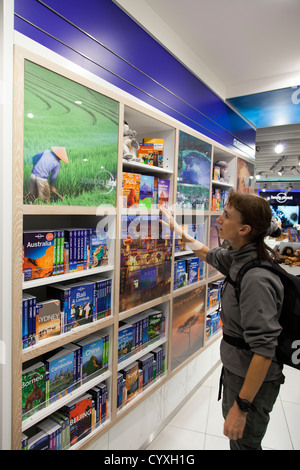 Backpacker Blick auf Lonely Planet Reiseführer im Lonely Planet Shop im Flughafen von Manchester, Manchester, UK. Stockfoto