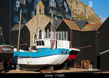 Ein kleines Boot gestrandet vor den Fischern Netto Läden in Hastings, England Stockfoto