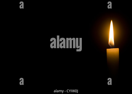 Brennende Kerze vor einem dunklen Hintergrund Stockfoto