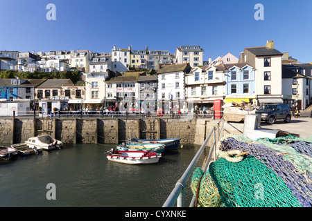 Die zwei Seiten der Brixham in Devon, England. Fischernetze liegen am Kai, neben kleinen Fischerbooten und Sportbooten. Stockfoto