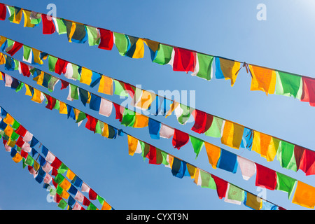 Buddhistische tibetische Gebetsfahnen im Wind gegen blauen Himmel winken Stockfoto