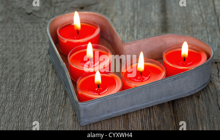 Rote brennende Kerzen auf ein Herz geformt Tablett Stockfoto