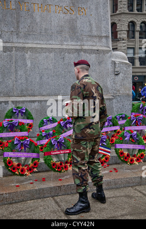 Ein Soldat schaut des Mohns und Kränze niedergelegt am Volkstrauertag am Ehrenmal in Vancouvers Siegesplatz. Stockfoto