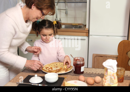 Mutter bereitet Crêpes mit kleinen Mädchen Stockfoto