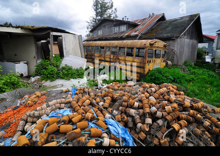 Fischernetz und Schulbus im Hinterhof eines Hauses in der Heimatgemeinde Tlingit von Kake, Alaska. Stockfoto