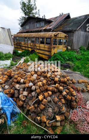 Fischernetz und Schulbus im Hinterhof eines Hauses in der Heimatgemeinde Tlingit von Kake, Alaska. Stockfoto