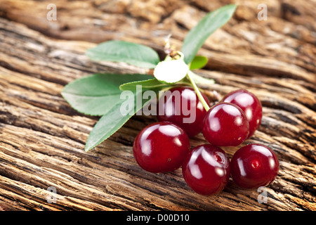 Kirschen mit Blättern auf einem alten Holztisch. Stockfoto