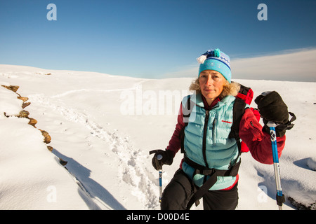 Eine Frau zu Fuß im Tiefschnee auf das Fairfield Hufeisen Anfang November, Lake District, Großbritannien. Stockfoto