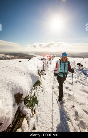 Eine Frau zu Fuß im Tiefschnee auf das Fairfield Hufeisen Anfang November, Lake District, Großbritannien. Stockfoto