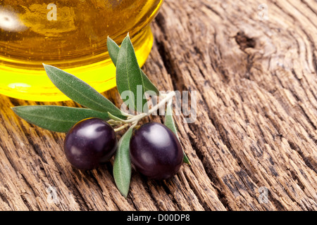 Reifen schwarzen Oliven mit Blättern auf einem hölzernen Hintergrund. Stockfoto