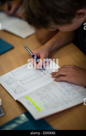 Schülerinnen und Schüler arbeiten auf Berechnungen in einer Mathematik-Klasse bei einer sekundären Gesamtschule, Wales UK Stockfoto