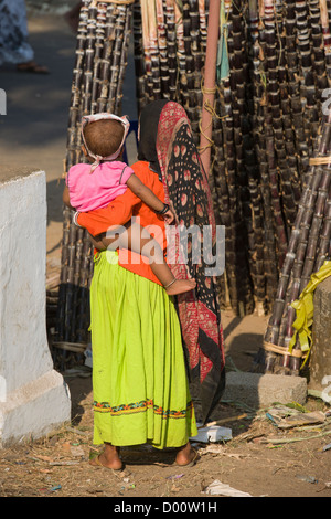 Frau in bunten Kleidern tragen ihr Kind betrachten Zuckerrohr auf dem Goureeswara-Tempel-Festival, Cherai, in der Nähe von Kochi (Cochin), Kerala, Indien Stockfoto