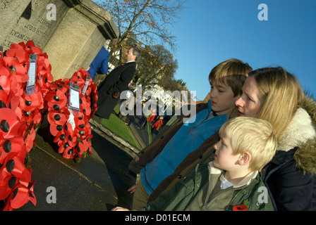 Mutter und Kinder durchlesen Kränze von Memorial auf das Gedenken Sonntag links, High Street, Haslemere, Surrey, Großbritannien. 11.11.2012. Stockfoto