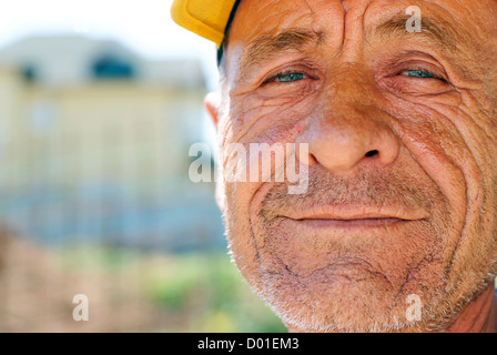 Alte faltige Mann mit gelber Kappe vor unscharfen Hintergrund Stockfoto
