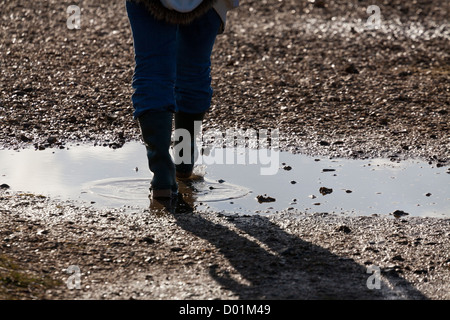 Beine von einer Person zu Fuß durch Pfützen auf einem Wanderweg Stockfoto