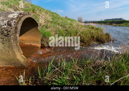 Wasser fließt aus einem Abflussrohr in einen kleinen Fluß Stockfoto