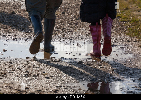 Beine von zwei Personen in Gummistiefel durch Pfützen auf einem Wanderweg zu Fuß Stockfoto